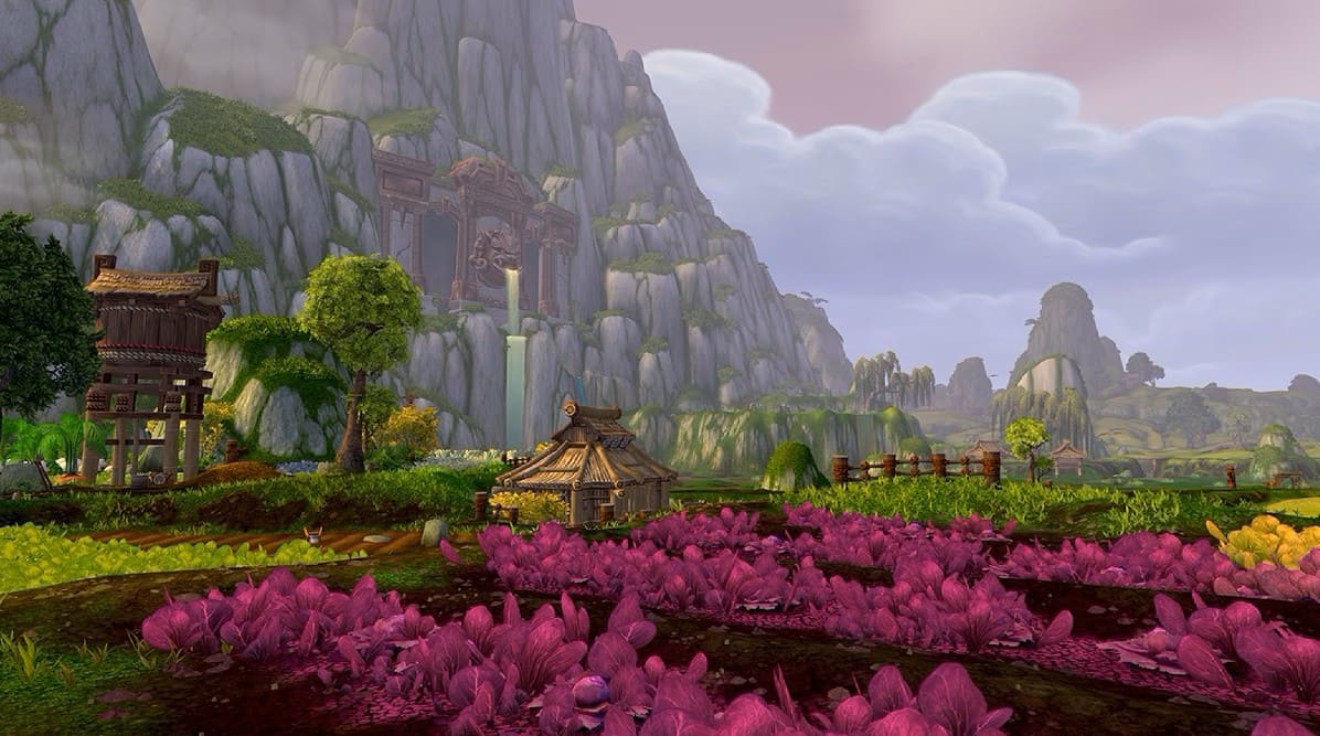 In game image of a farm next to a mountain. It has a house, waterfall and a field of pink flowers.